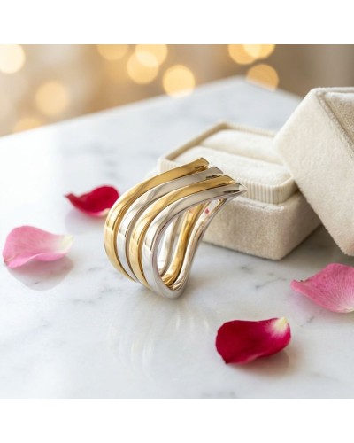 Alliance SERPENTINE bicolore en or: bracelet torsadé doré et argenté posé près d'une boîte à bijoux, pétales roses autour.