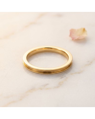 Alliance fine incurvée pour femme en or sur fond marbré, accentuée par pétale rosé en arrière-plan.