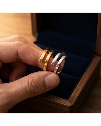 Alliance entrelacée bicolore pour homme or et argent, présentée sur le doigt avec boîte en bois.