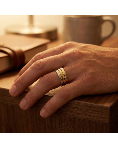 Alliance entrelacée bicolore homme porte sur ledo main: bague dorée et argentée sur doigt masculin, fond bois et tasse.