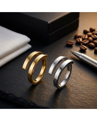 Alliance entrelacée bicolore homme or : deux bagues modernes, dorée et argentée, posées sur une surface sombre avec grain, café