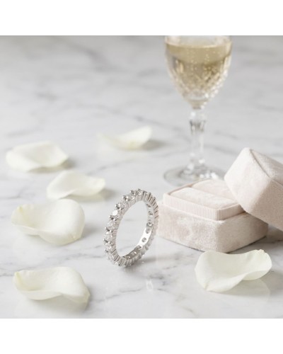 Alliance serti griffes sur tout le tour: bague diamant en or blanc, entourée de pétales et d'une coupe de champagne au fond.
