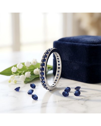 Alliance tour complet en serti grains avec 32 saphirs synthétiques en or, bracelet argenté et perles bleues sur marbre.