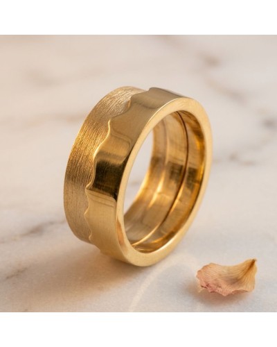 Alliance bi-matière femme en or: bague délicate en or bicolore avec texture mate et dentelure unique, sur marbre avec feuille sè