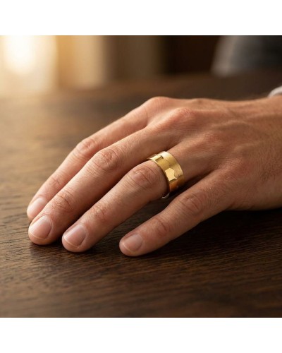 Alliance homme en or bi-matière, large bande dorée sur doigt posé sur bois.