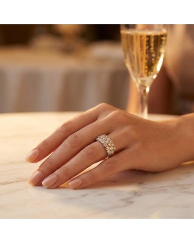 Alliance pavée de 19 diamants portée sur le doigt, devant un verre de champagne.
