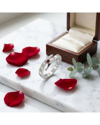 Alliance CROISADE en or avec rubis synthétique, cadrée près d’un écrin en bois et pétales rouges sur marbre.