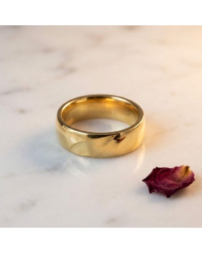 Alliance large bombée homme en or brillants sur marbre jaune, avec fleur séchée pour décor.