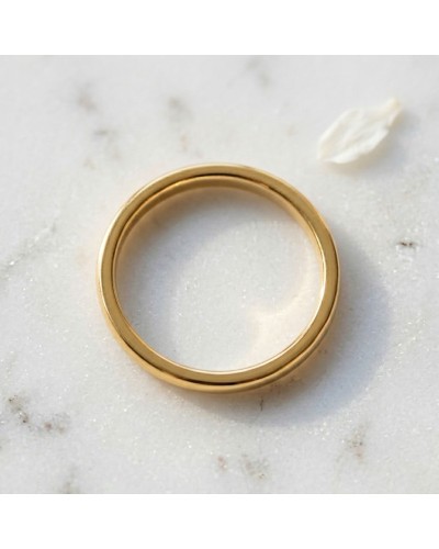 Alliance bombée fine pour femme en or - bague dorée simple sur fond clair.