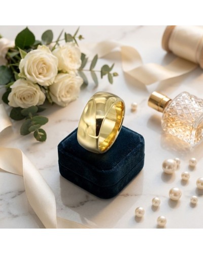 Alliance large bombée femme en or posée sur un écrin bleu nuit, entourée de roses blanches et d’accessoires dorés.