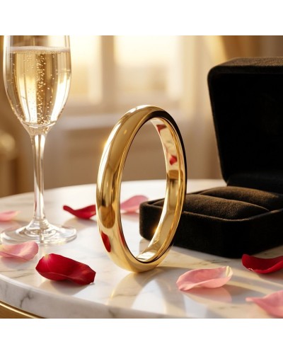 Alliance bombée fine homme en or sur socle blanc, près d’un verre de champagne et d’un écrin noir, pétales sur la table.