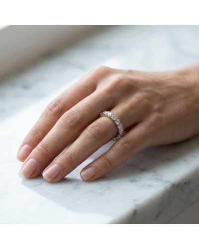 Alliance tour complet avec griffes extérieures sertie de 20 diamants sur doigt féminin, près d'une surface en marbre.