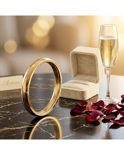 Alliance moyennement bombée homme en or posé sur un meuble avec boîte à bagues et verre de champagne, pétales rouges.