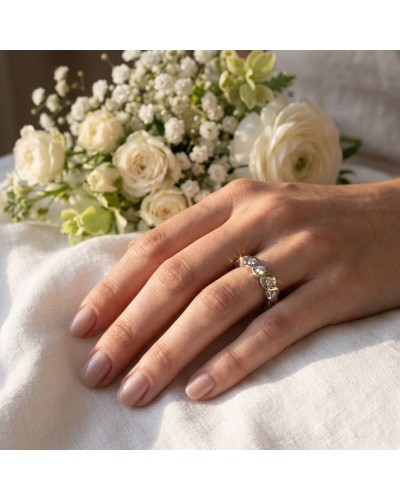 Alliance en vague sertie de 9 diamants sur une main féminine, entourée de fleurs blanches.
