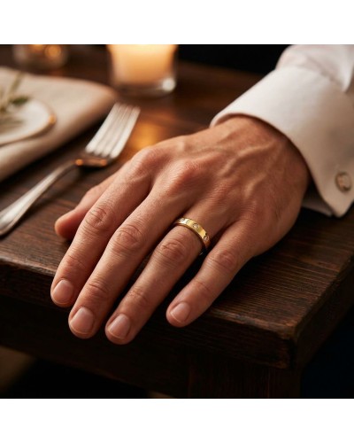 Alliance homme en or sertie de 4 diamants portée sur le doigt, posé sur une table en bois.
