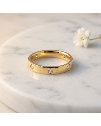 Alliance homme doré avec quatre diamants sertis, présentation sur marbre blanc.