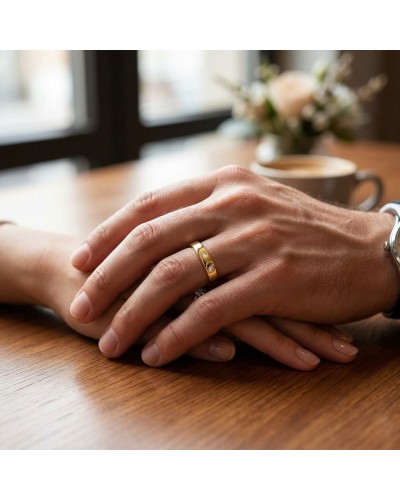 Alliance homme en or avec deux diamants, mains croisées sur une table.