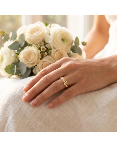Alliance vague sertie de 13 diamants sur une main féminine, avec bouquet blanc en arrière-plan.