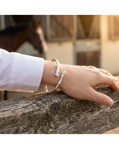Bracelet galop en argent rhodié serti de 57 oxydes blancs Equimasters porté sur le poignet, posé sur une pièce de bois.