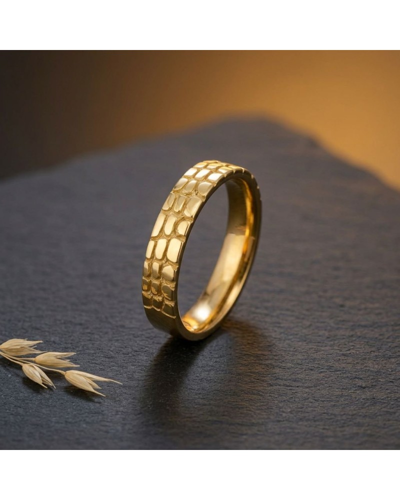 Alliance demi-effet crocodile en or pour homme, bague dorée à motif peau de croco sur surface sombre.