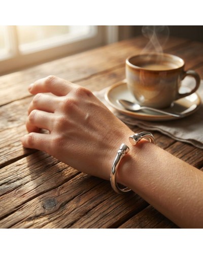 Bracelet GALOP en argent rhodié porté au poignet sur une table en bois près d’une tasse de café fumante.