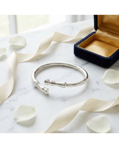 Bracelet GALOP en argent rhodié, ouvert sur une surface blanche avec boîte à bijoux bleu et ruban crème autour.