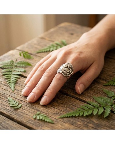 Bague TORTUE en argent portée sur le doigt, motif coquille de tortue, posé sur une table en bois avec des fougères.