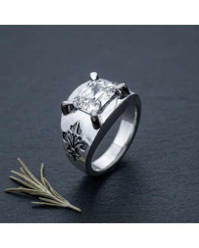 Bague MENTAWAÏ en argent avec pierre centrale dégagée, griffes apparentes et ornement feuillagé gravé sur la face, posée sur une