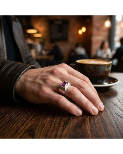 Bague HARAPAN avec pierre violet brillant portée sur le doigt d’une main posée sur une table de café.