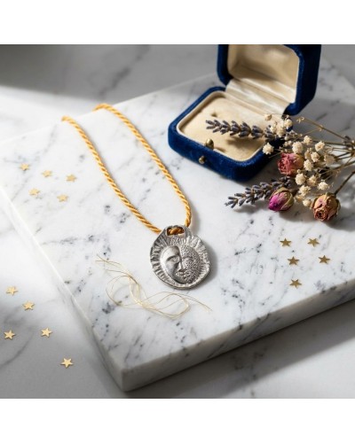 Pendentif Zodiaque GEMEAUX sur cordon doré, présenté près d’une boîte bleue et de fleurs séchées; fermoir offert apparaissant av