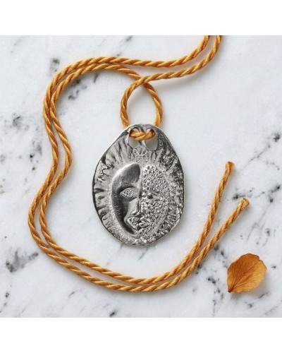 Pendentif zodiaque Gémeaux en métal argenté avec cordon orange et fermoir offert, posé sur marbre.