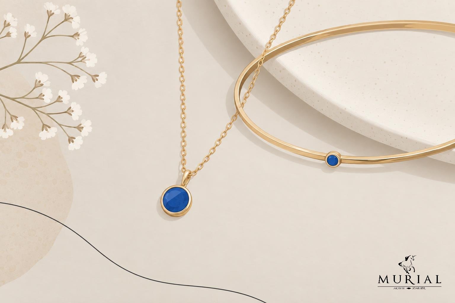 Collier à chaîne dorée avec pendentif bleu rond et bracelet doré assorti posé sur une plaque beige.